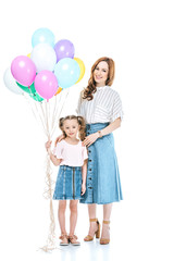 beautiful mother and cute little daughter with colorful balloons smiling at camera isolated on white