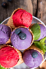 Ice cream, Blueberry and Raspberry scoop in cone on wooden table.  