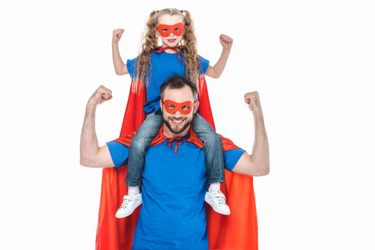 happy super father and daughter in masks and cloaks smiling at camera isolated on white
