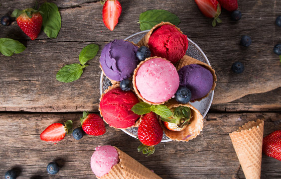 Ice cream, Blueberry and Raspberry scoop in cone on wooden table.  