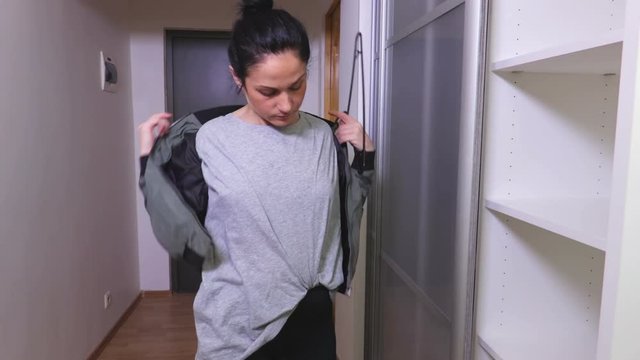Woman take off bomber jacket near wardrobe
