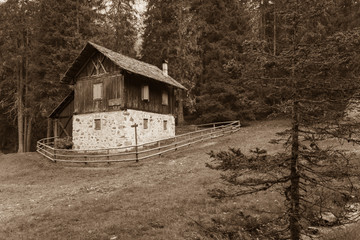 A closed old cowshed at fall in front of a mountain meadow