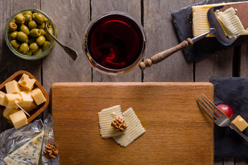 Palette of many types of cheese and some grapes, olives and wine with copy space.