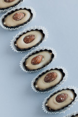 Flat lay of delicious praline sweets with almonds on blue background