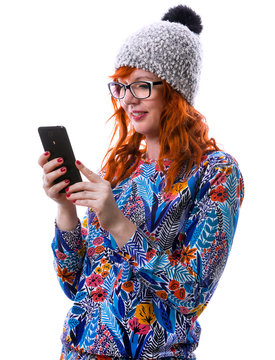 Portrait of a smiling hipster red hair girl reading messages or watching video on mobile phone, isolated over a white background.