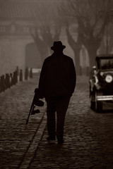 Silhouette of a gangster with machine gun, on a street with fog - obrazy, fototapety, plakaty