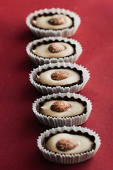 Flat lay of delicious praline sweets with almonds on red background