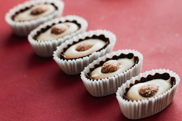 Flat lay of delicious praline sweets with almonds on red background