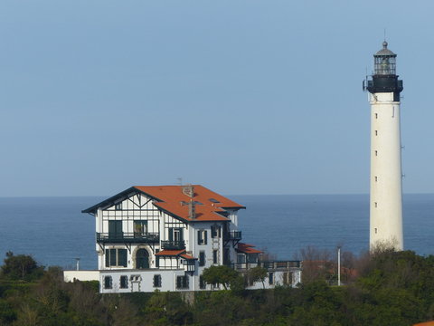 Casa caratteristica del Paese Basco francese con accanto un faro bianco sul mare, Francia.