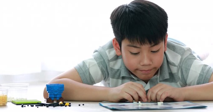 Cute asian boy playing plastic block at home with smile face.