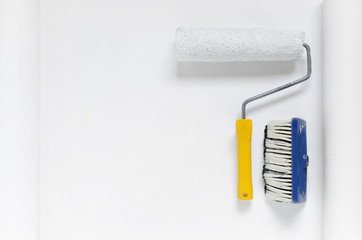 paint roller and a brush on white wallpaper roll with copy space