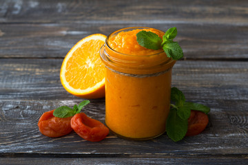 Healthy raw orange jam with dried apricots in a glass jar with cookies on a wooden table. diet food. selective focus. free space. rustic style