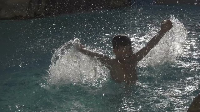 silhouette of boy splashing water in poool