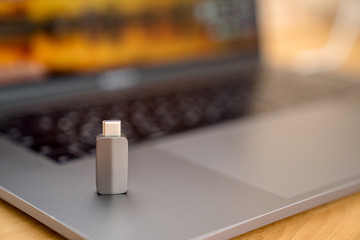 Gray Thunderbolt USB-C Adapter on the gray keyboard on laptop background. Digital technologies and...