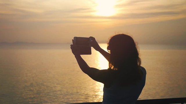 Girl takes selfie of sunset on mobile phone camera while has traveling on cruise ship. slow motion. 1920x1080