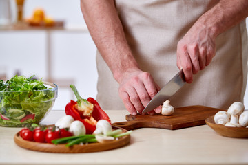 Obraz na płótnie Canvas Man cooking at kitchen making healthy vegetable salad, close-up, selective focus.