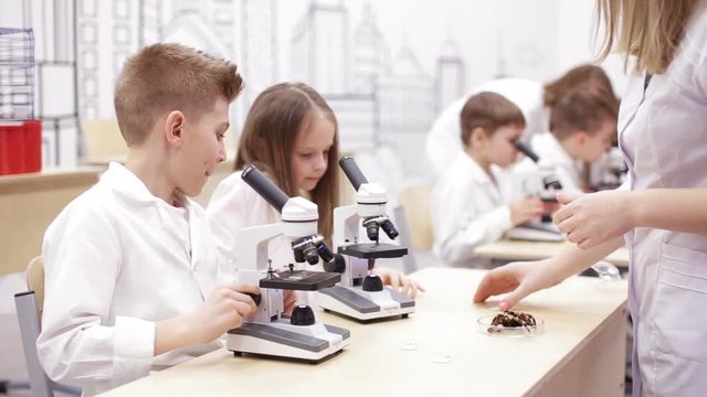 School children learn to work with a microscope