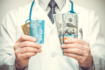 Doctor holding credit cards in his left and USA dollars in his right hand