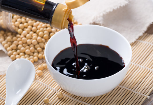 Close up of pouring soy sauce in white bowl 
