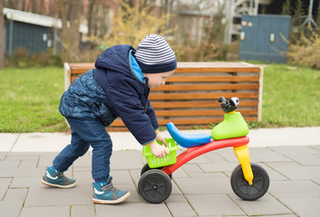 Happy little boy push his bike