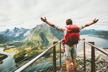 Happy man raised hands enjoying aerial mountains landscape Travel Lifestyle adventure vacations success emotions in Norway traveler with backpack standing alone on Rampestreken viewpoint in Norway