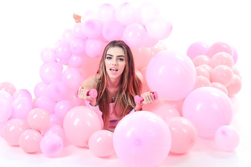 Fototapeta na wymiar Young woman laying in pink balloon. Girl with colorful balloons. Sport concept. Girl with dumbbells. Sport costume. Healthy lifestyle. Blonde woman in sport dress with pink balloons. Sport costumes.