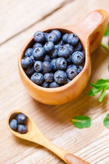 Blueberries in wooden mug Kuksa is Ancient Lapland Finnish Wooden Drinking Cup on old wooden table, close-up