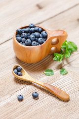 Blueberries in wooden mug Kuksa is Ancient Lapland Finnish Wooden Drinking Cup on old wooden table, close-up