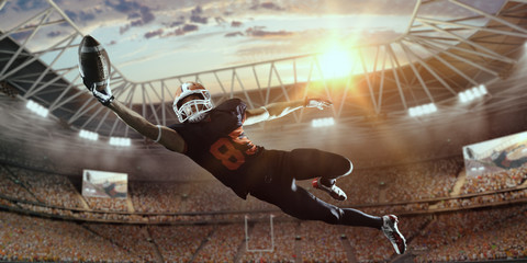 American football player jumps and catches the ball in flight in professional sport stadium