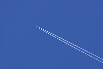 airplane with vapor trail in blue sky