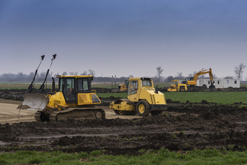 Excavators and bulldozers preparing the ground for the construction of a factory
