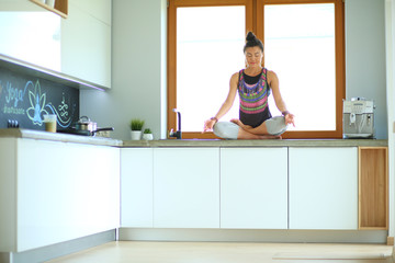 Young beautiful woman sitting at the kitchen table in the lotus position. Woman. Yoga