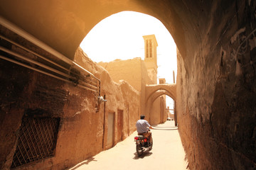 Iran Yazd. A motorcyclist rides through an ancient adobe street