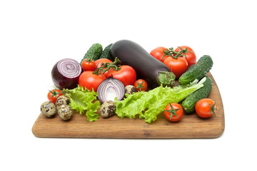 vegetables and quail eggs on a cutting board on a white background