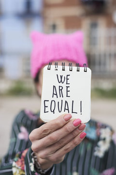 woman with a pink hat and the text we are equal.