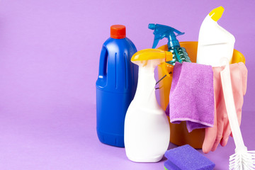Cleaning bucket with cleaning agent and cleaning cloth on purple background