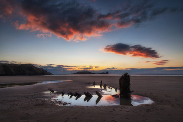 Sunset at Worms Head and the wreck of the Helvetia, at Rhossili Bay on the Gower peninsula, South Wales, UK