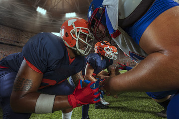 American football players preforms an action play in professional sport stadium