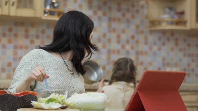 Adorable little girl helps mother at the kitchen