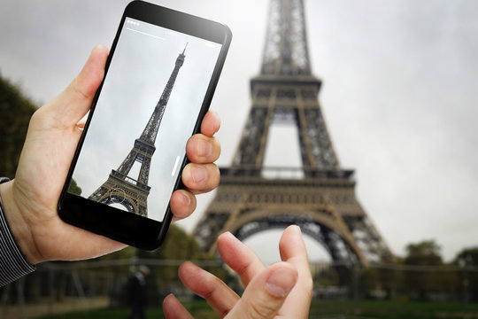 traveler hand taking a photo of Eiffel Tower with smartphone during a weekend trip to Paris, France