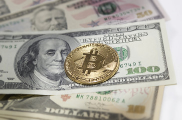 Golden bitcoin coin on us dollars close up.