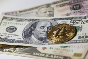 Golden bitcoin coin on us dollars close up.