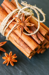 Close up of tied cinnamon sticks and anise star, Black slate background.