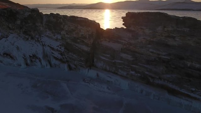 Beautiful Bright sunset rock mountain Olkhon Baikal blue ice crack surface texture drawing. Mountains splashes innocent landscape. Liberty freedom. Traveling tourism. Winter snow frosty Aerial Above