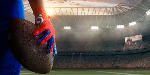 Obraz na płótnie Canvas American football players hand with ball in professional sport stadium 