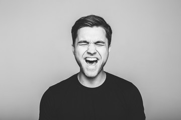 Anger, rage, shout  man  standing  on  grey background.