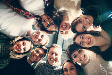 Happy friends lying together in circle looking at camera, keeping hands  and smiling while lying on wooden floor.. Concepts about friendship,lifestyle,unity,business and teamwork. - obrazy, fototapety, plakaty