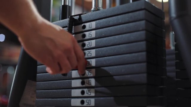 Close up shot hand man stacks of weight plates action active black bodybuilding cable change club exercise fit gym health healthy heavy workout iron kilogram lifting machine metal