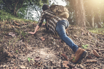 Young Traveler with backpack are climbing with mountain in forest on background , Lifestyle hiking concept