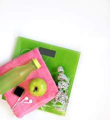 Healthy lifestyle for women diet with sport equipment, sneakers, scale weight, fresh water, dumbbells, pink towel. Green apples and orange. Healthy and Diet Concept.